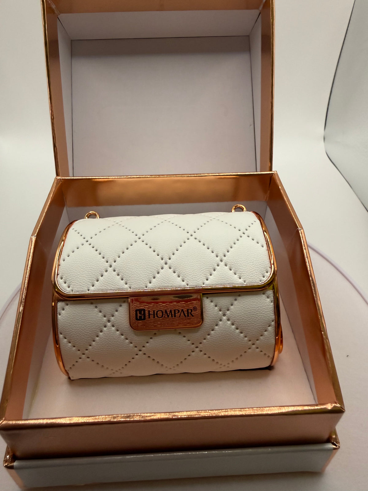 White quilted-style lipstick case with gold-tone trim in its box